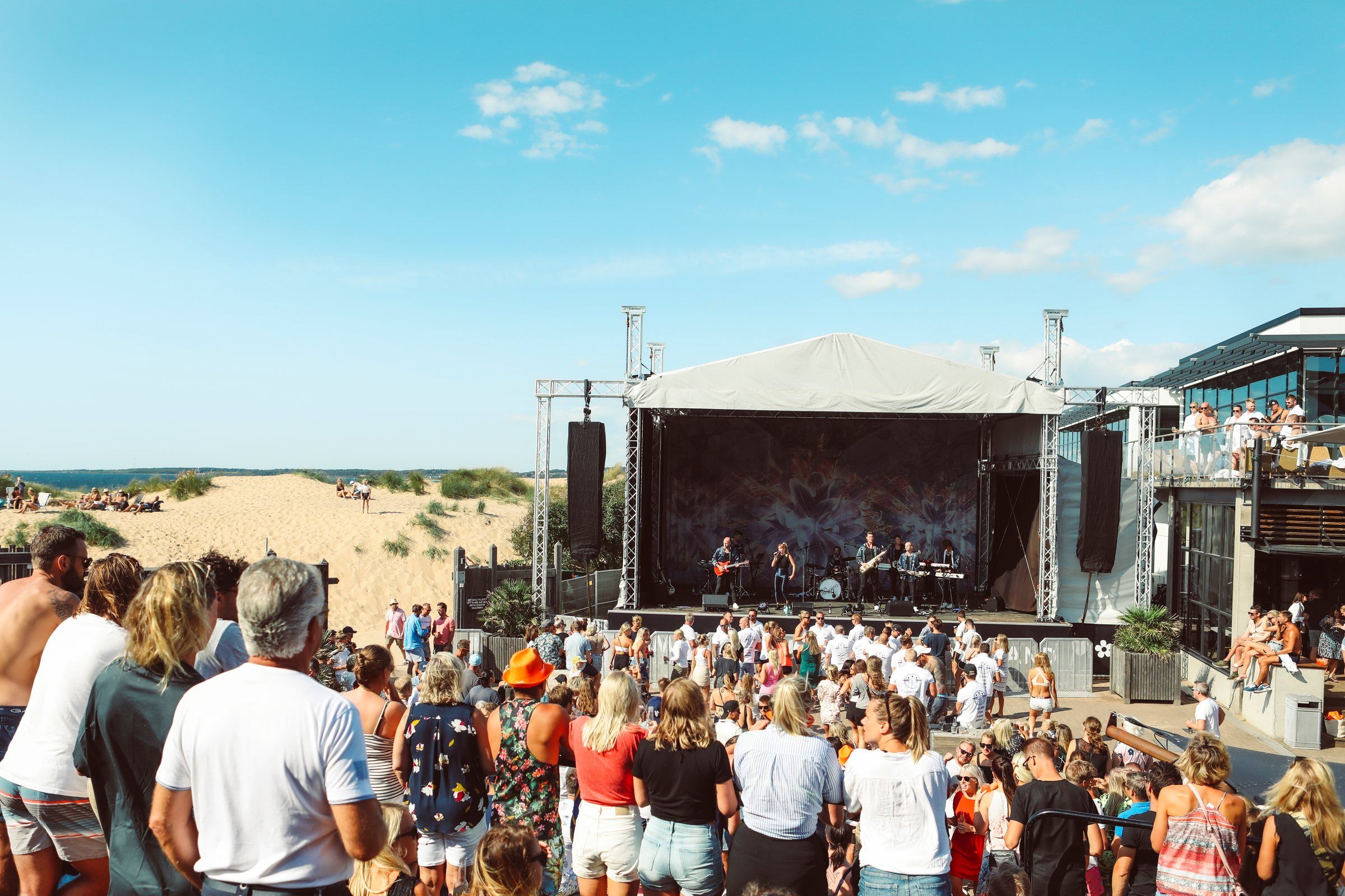 Utomhusscenen bland sanddynerna med publik i solen